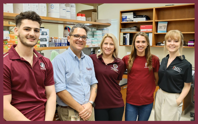 Five people smiling together in the Chelko laboratory.