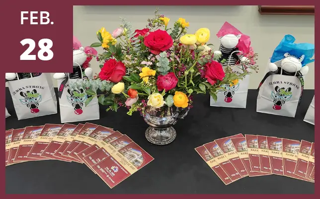 Rare Disease Day information table with brochures, flowers, and gift bags