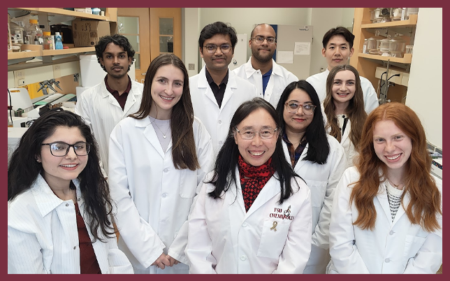 A group of researchers in white lab coats posing in a laboratory