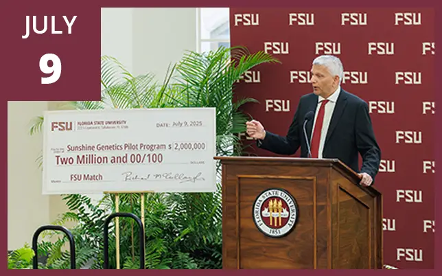A man in a dark suit and red tie speaks from a wooden podium featuring the Florida State University (FSU) seal. To his left is a large ceremonial check for $2,000,000 made out to the 