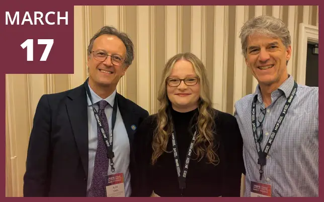Three people smile together in a photo with a maroon border featuring the date 